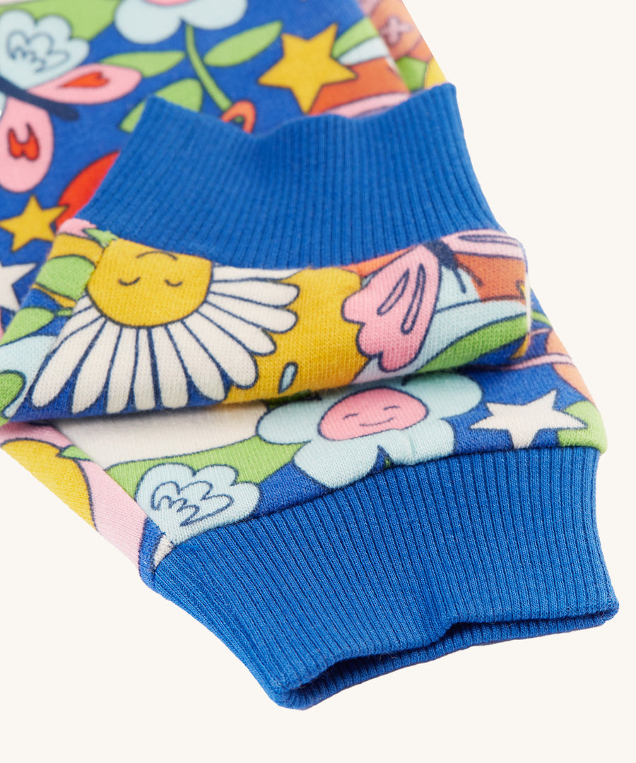 A closer look at the blue, ribbed elasticated ankle cuffs on the Frugi Snuggle Crawlers - Retro Happy. The image also shows the Retro Happy print on the trouser legs