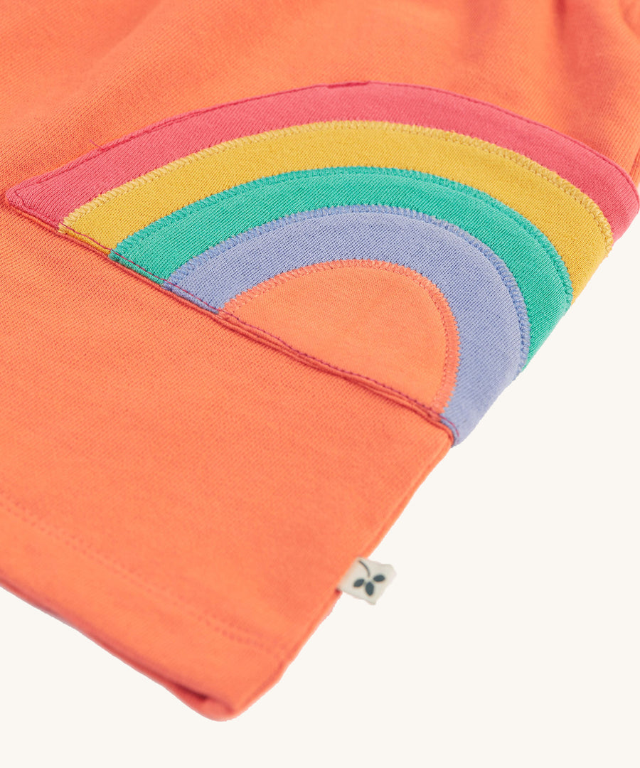 A closer look at the applique rainbow pockets on the Frugi Sybil Skirt - Cantaloupe/Rainbow. The rainbow colours are red, yellow, green and blue