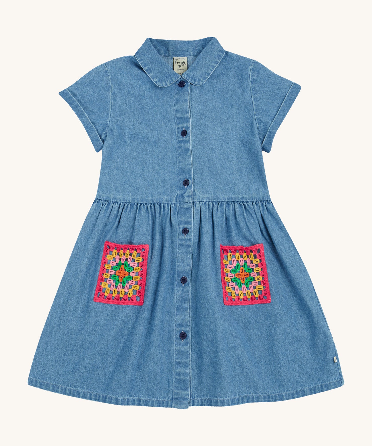 Frugi blue denim dress crochet pocket design on a cream background.