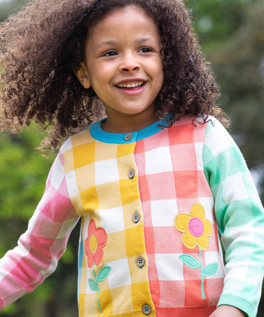 Frugi multicoloured check button cardigan daisy design on a cream background.