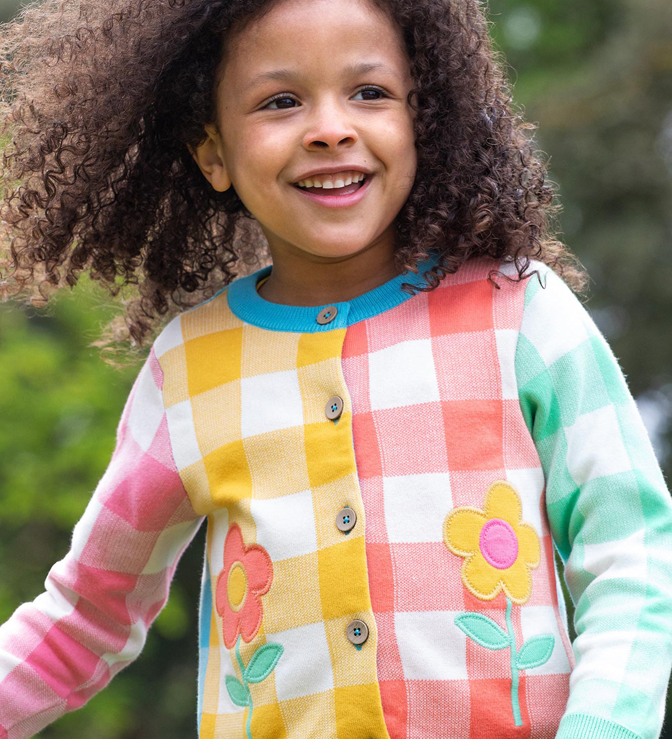 Frugi multicoloured check button cardigan daisy design on a cream background.