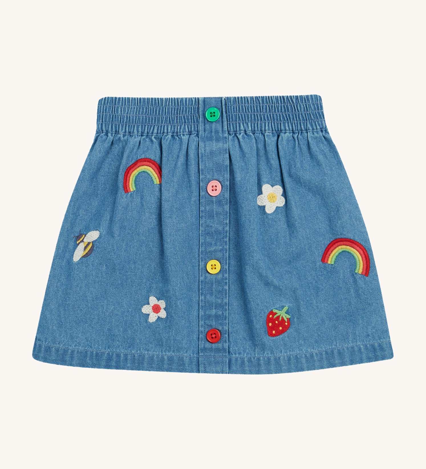 Frugi kids denim skirt with a flower, rainbow and strawberry design on a cream background.