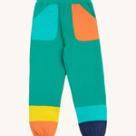 Frugi green joggers with a blue, orange yellow and green colour block design back detail on a cream background.