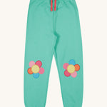 Frugi green crawler joggers daisy design on a cream background.