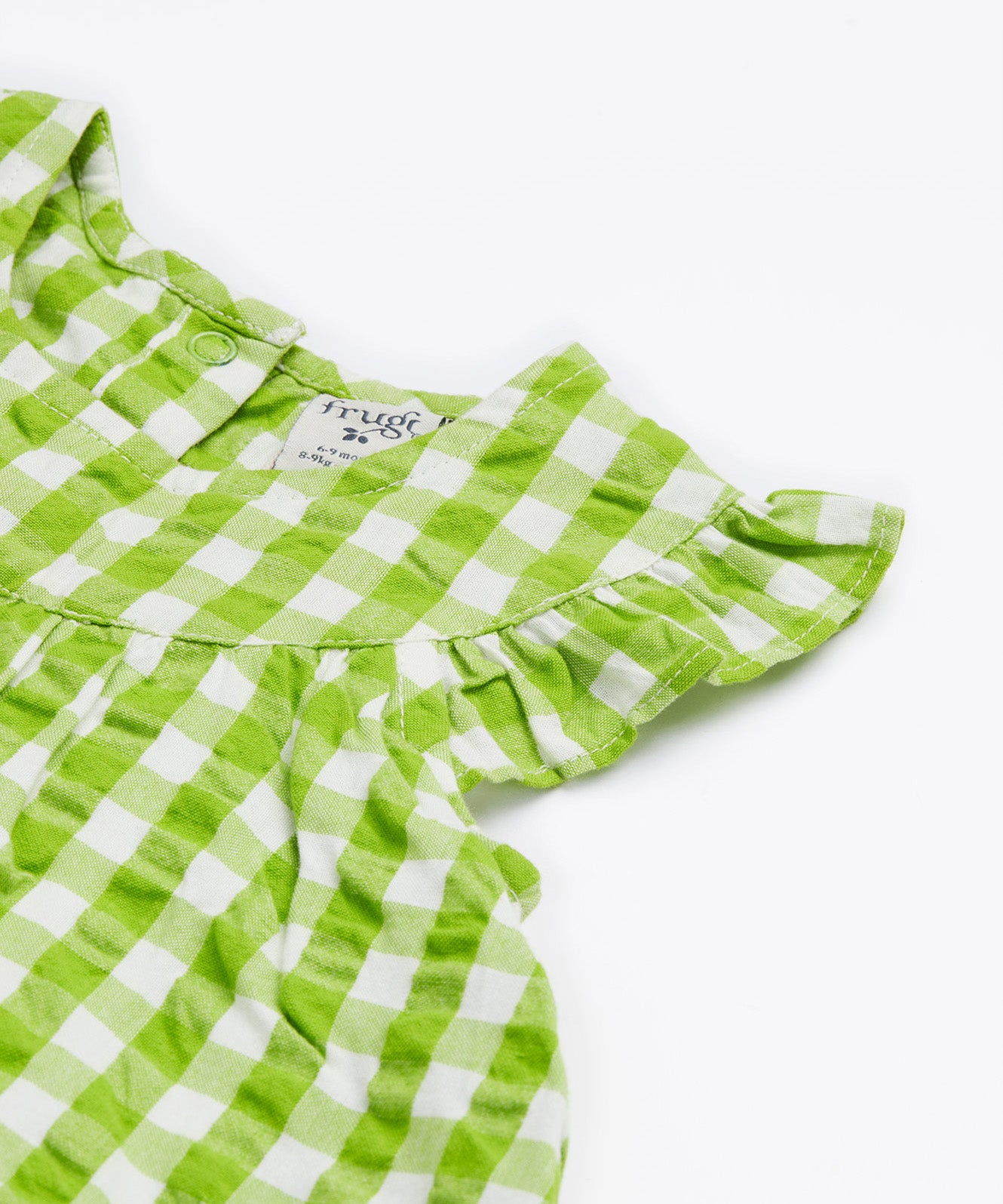 Close up of the Frugi little kids green gingham, donkey myrtle body dress - showing the gentle frill and back popper fastener detail on green and white gingham organic cotton fabric