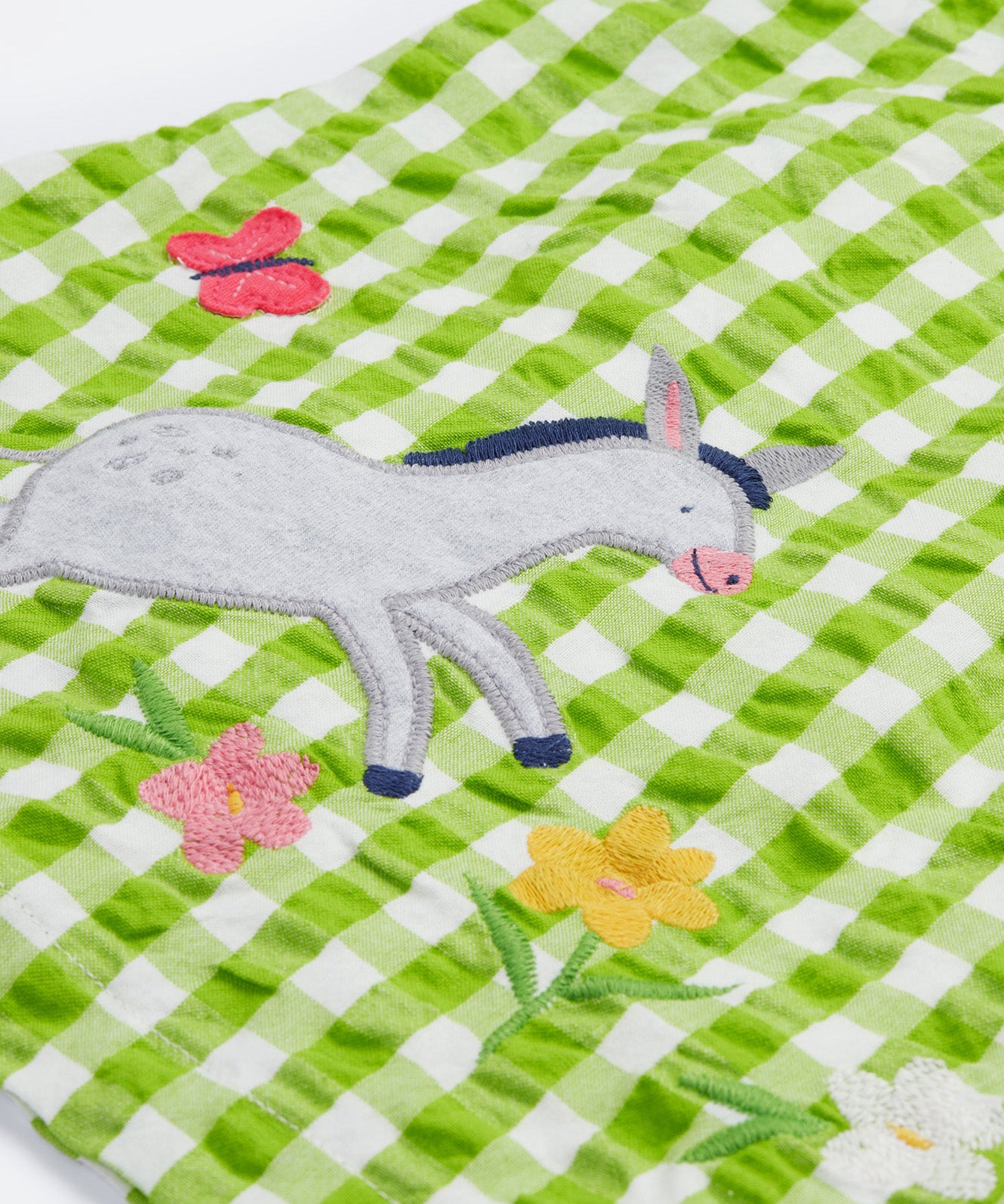 Close up of the Frugi little kids green gingham, donkey myrtle body dress - showing a grey donkey appliqué on green and white gingham organic cotton fabric