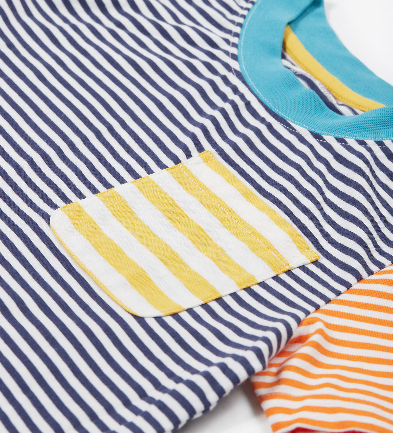 Close up of theFrugi kids hopscotch stripe pocket t-shirt showing the front pocket detail and light blue neck trim on striped organic cotton fabric