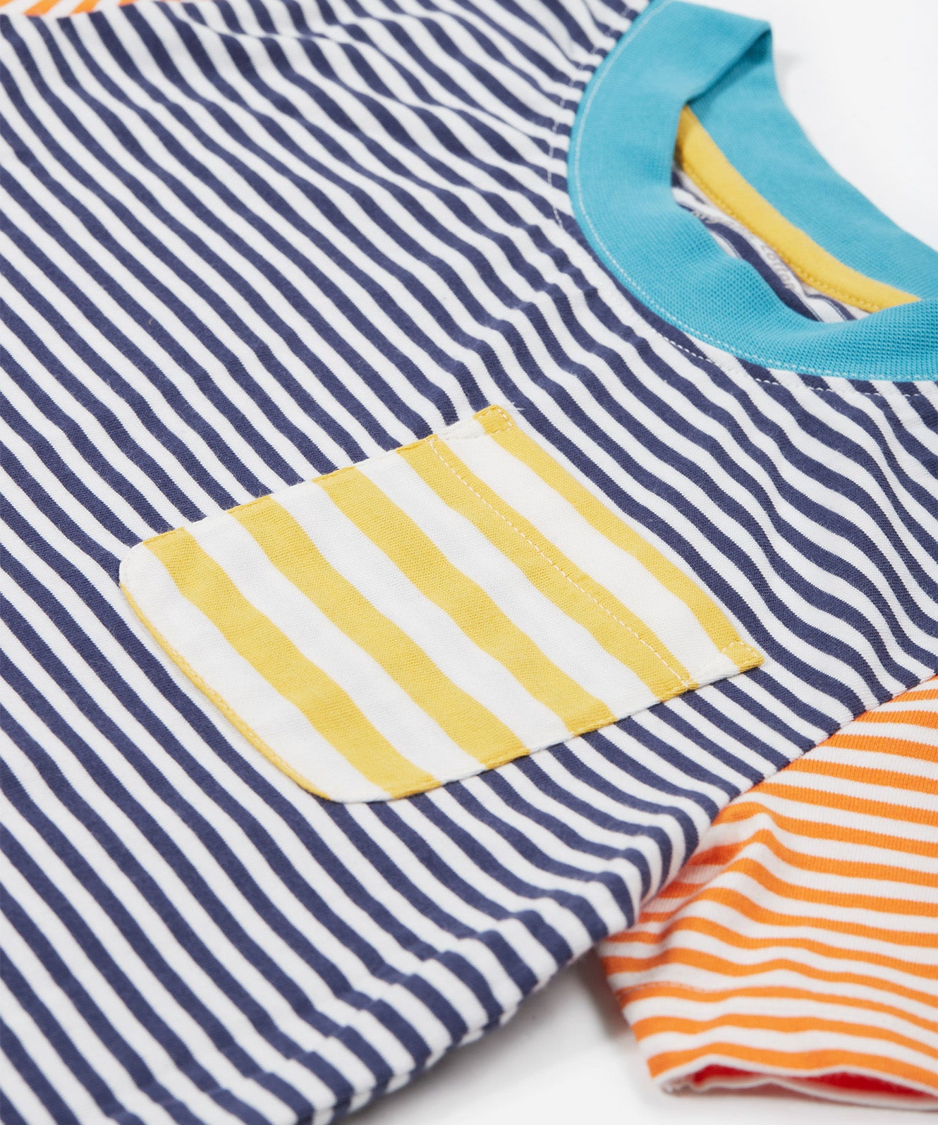 Close up of theFrugi kids hopscotch stripe pocket t-shirt showing the front pocket detail and light blue neck trim on striped organic cotton fabric