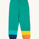 Frugi green joggers with a blue, orange yellow and green colour block design on a cream background.