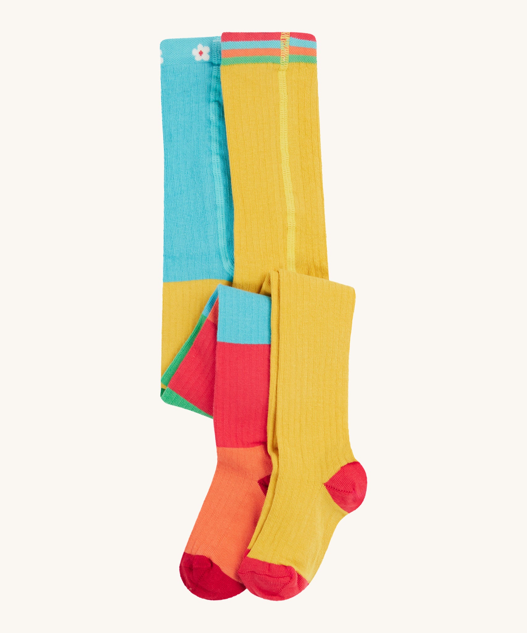 Frugi 2 pack ribbed tights in a rainbow colour block design on a cream background.