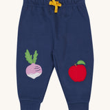 Frugi navy crawler joggers veg design on a cream background.