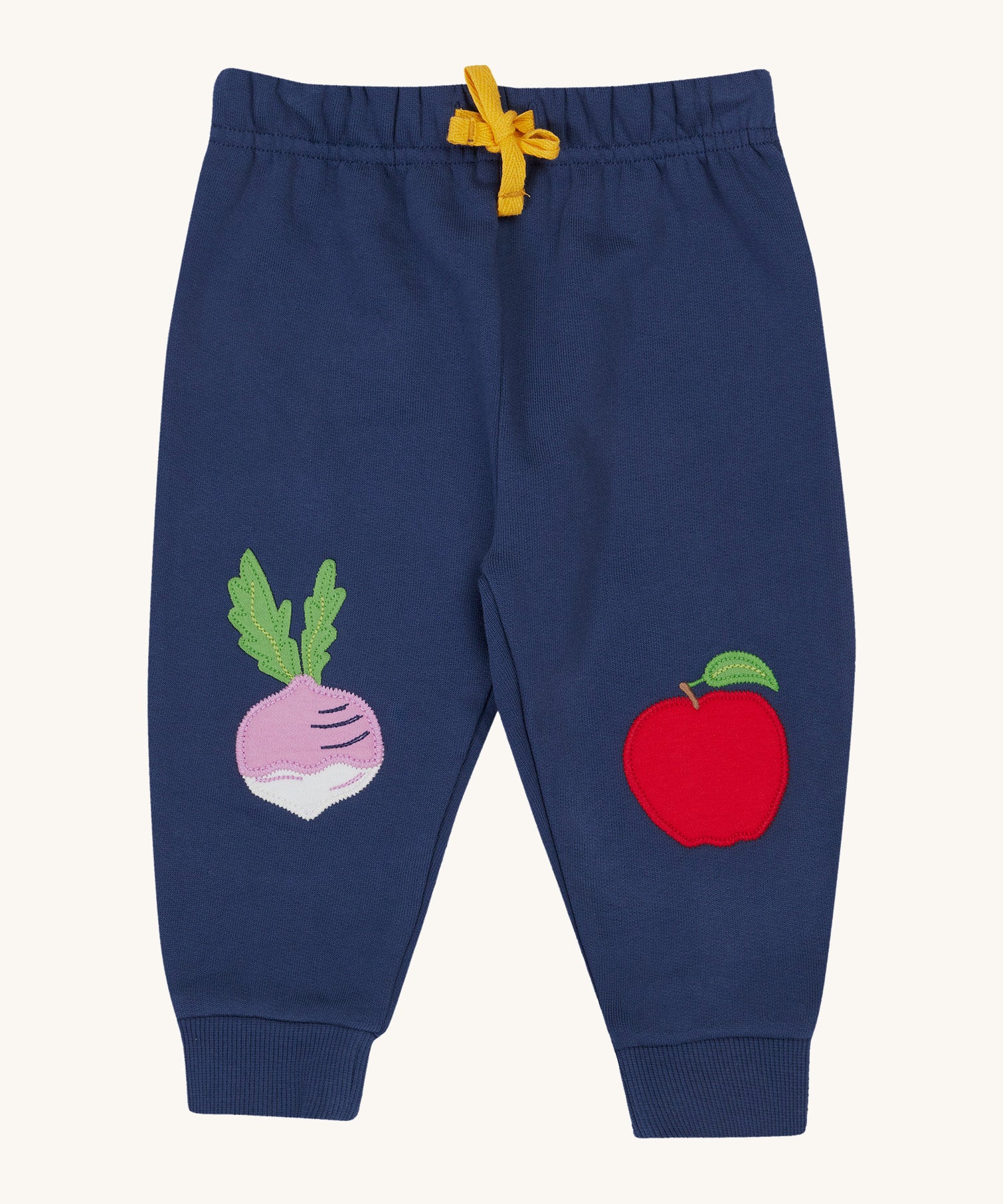 Frugi navy crawler joggers veg design on a cream background.