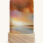 The Golden Sunset illustration by Baukje Exler sat in a Toverlux Magic Lantern base, on a cream background