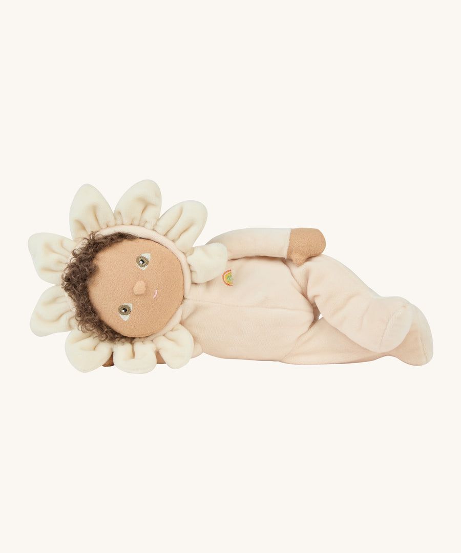 The light cream dinky dinkum doll lying down on a cream background.