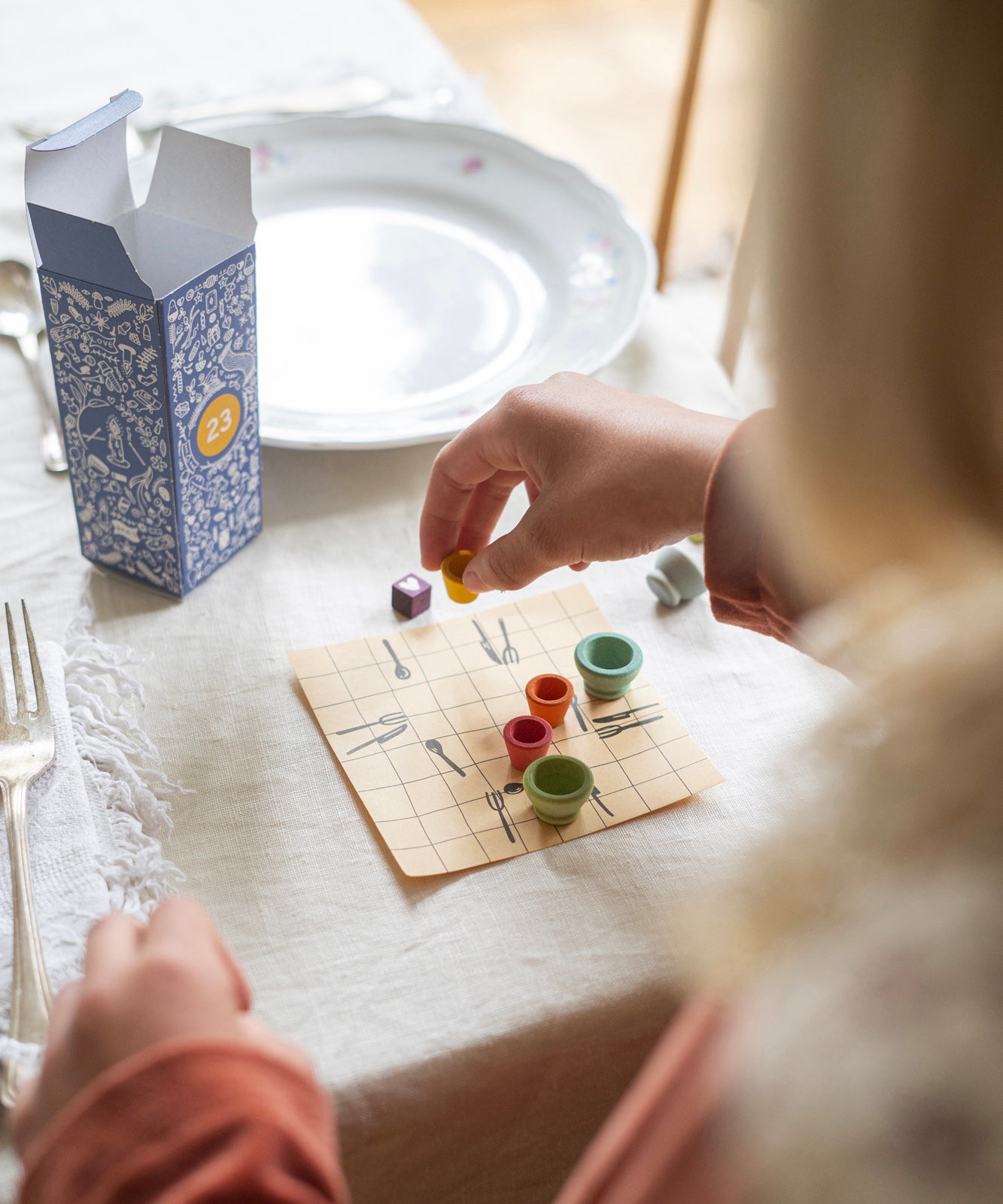 A child playing with the small wooden pots from the Grapat advent calendar 2024, on a table