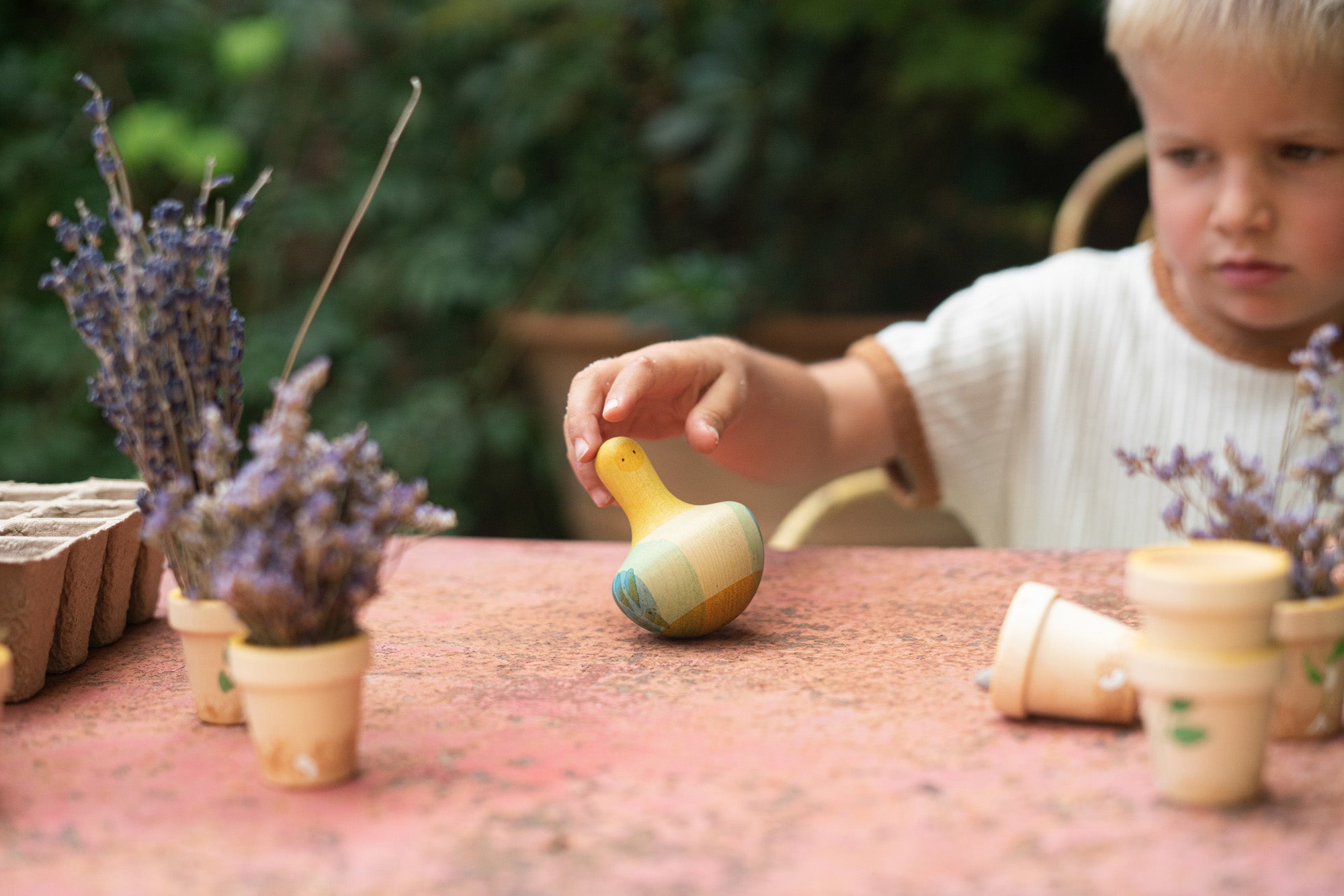 A child playing with the Grapat wooden yellow flowing bird outside on a table