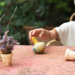 A child playing with the Grapat wooden yellow flowing bird outside on a table