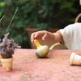 A child playing with the Grapat wooden yellow flowing bird outside on a table