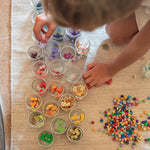 A child sorting the Grapat wooden mis and match bloom set into little jars