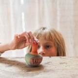 A child playing with the Grapat wooden mellow orange bird on a wooden table