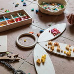 A child playing with the Grapat wooden bloom mis and match wooden block set on wooden Grapat petals and a basket on the floor