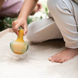 A child playing with the Grapat wooden yellow flowing bird outside in a sandpit bird detail