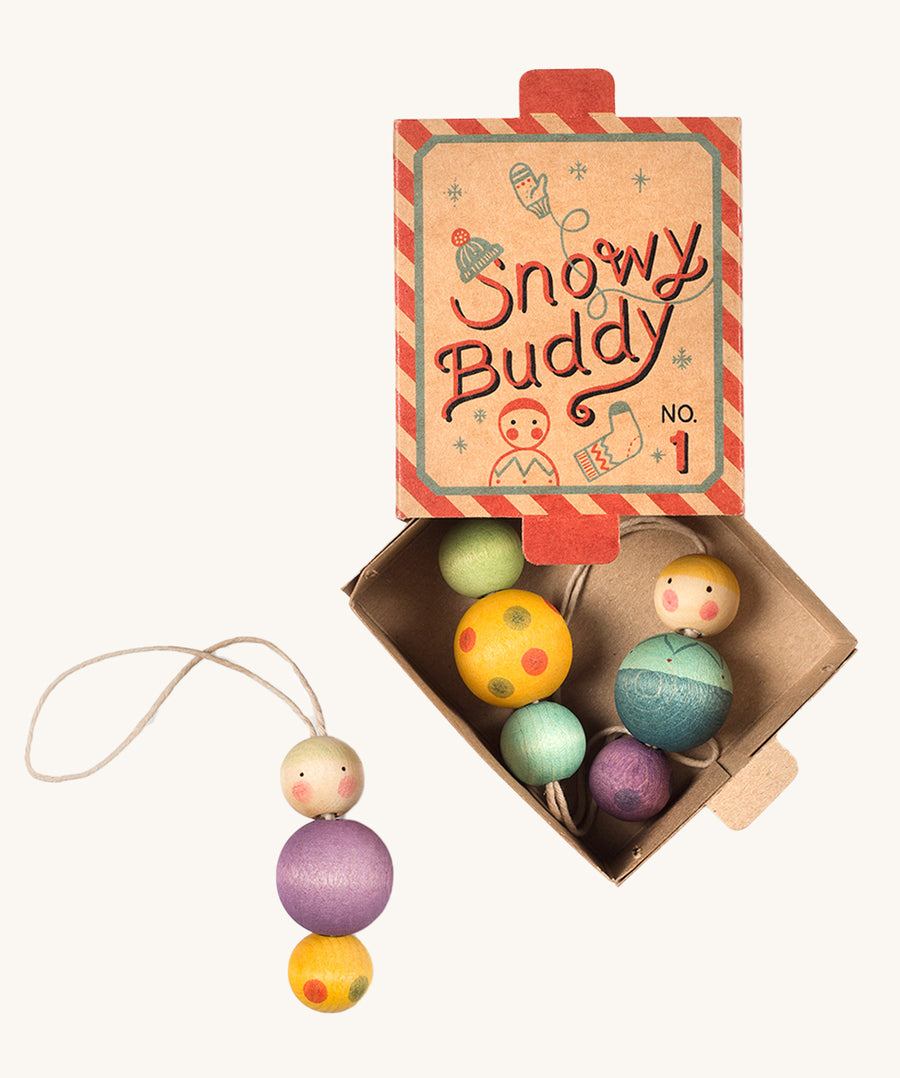 A red and blue striped cardboard box for the snow buddy wooden Grapat decorations on a cream background.