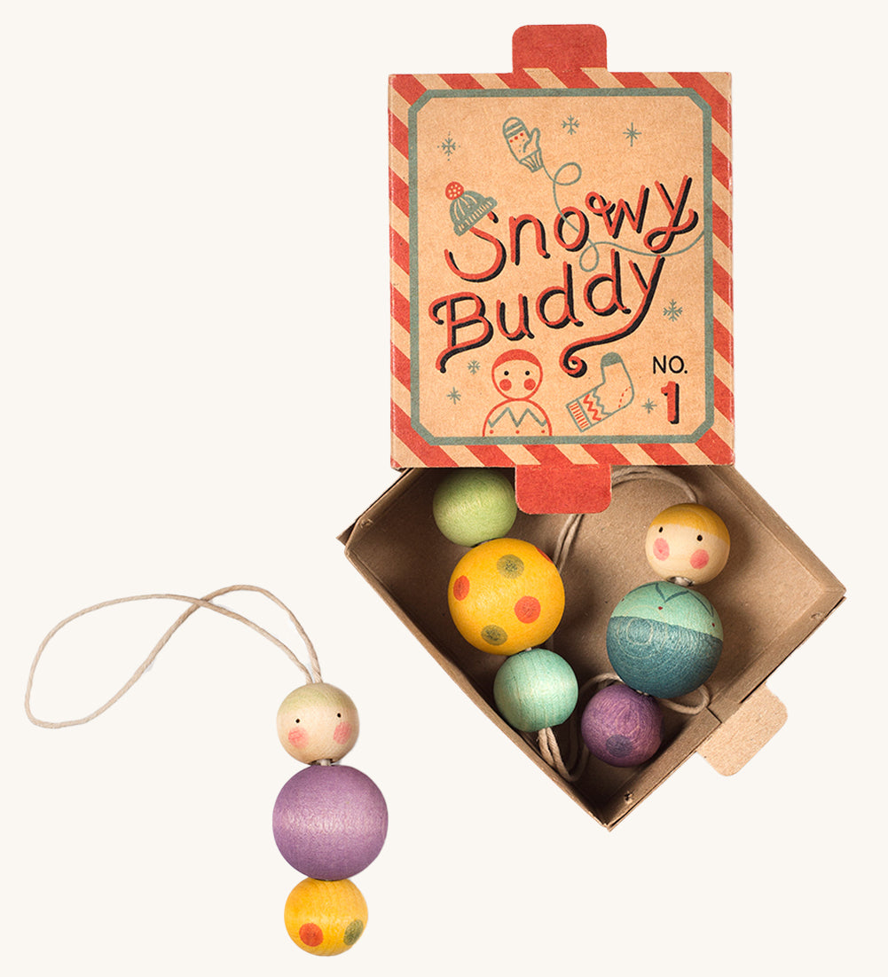 A red and blue striped cardboard box for the snow buddy wooden Grapat decorations on a cream background.