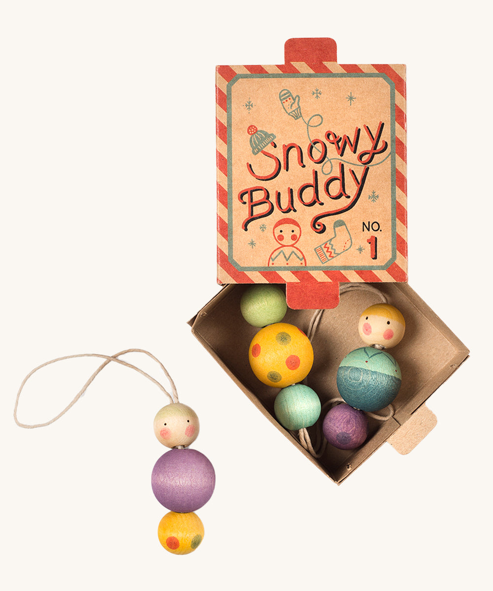 A red and blue striped cardboard box for the snow buddy wooden Grapat decorations on a cream background.