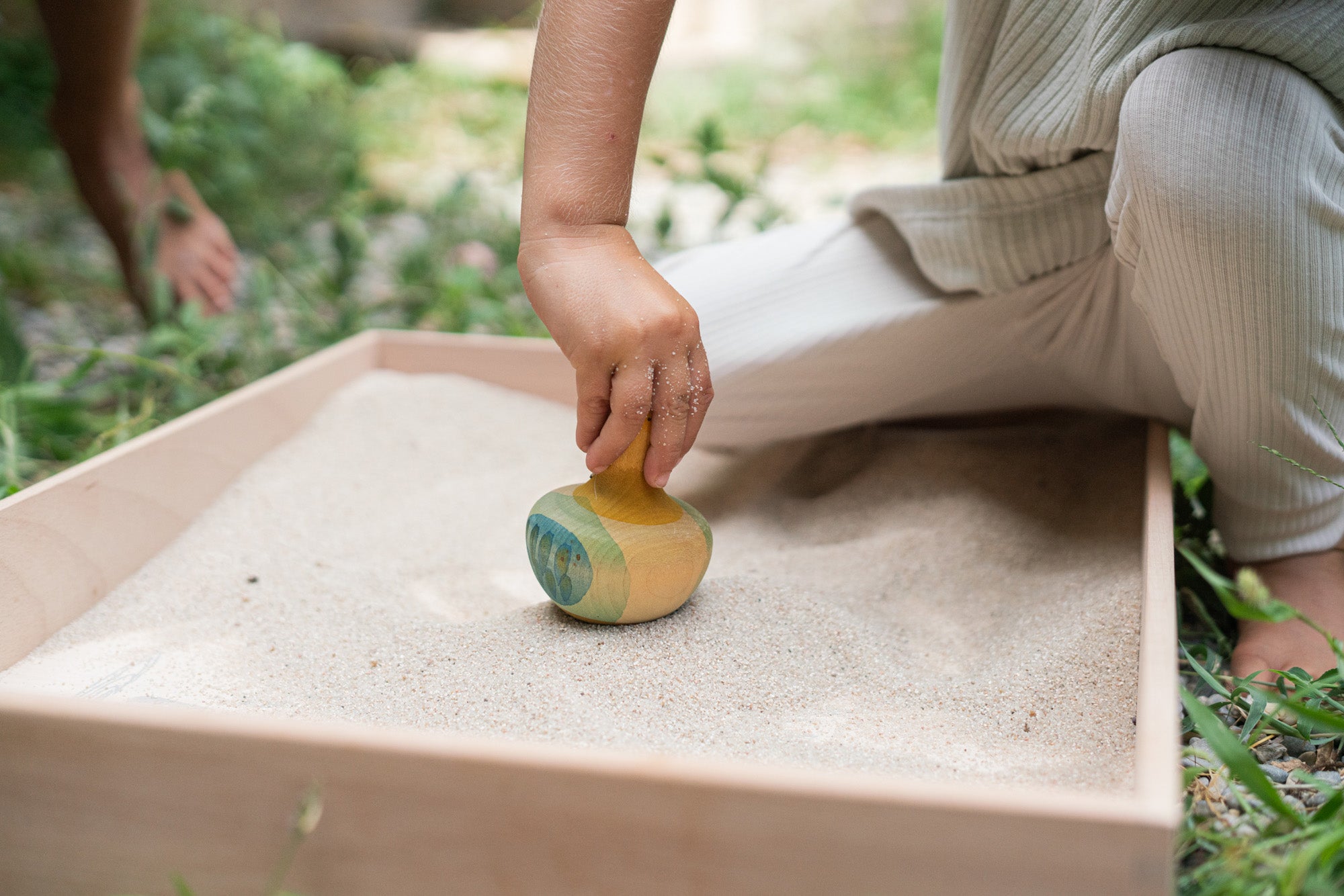 A child holding the Grapat wooden yellow flowing bird outside 