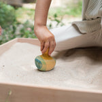 A child holding the Grapat wooden yellow flowing bird outside 