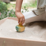 A child holding the Grapat wooden yellow flowing bird outside 