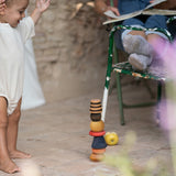 A child playing with the Grapat serendipity wooden stacking set outside on the floor