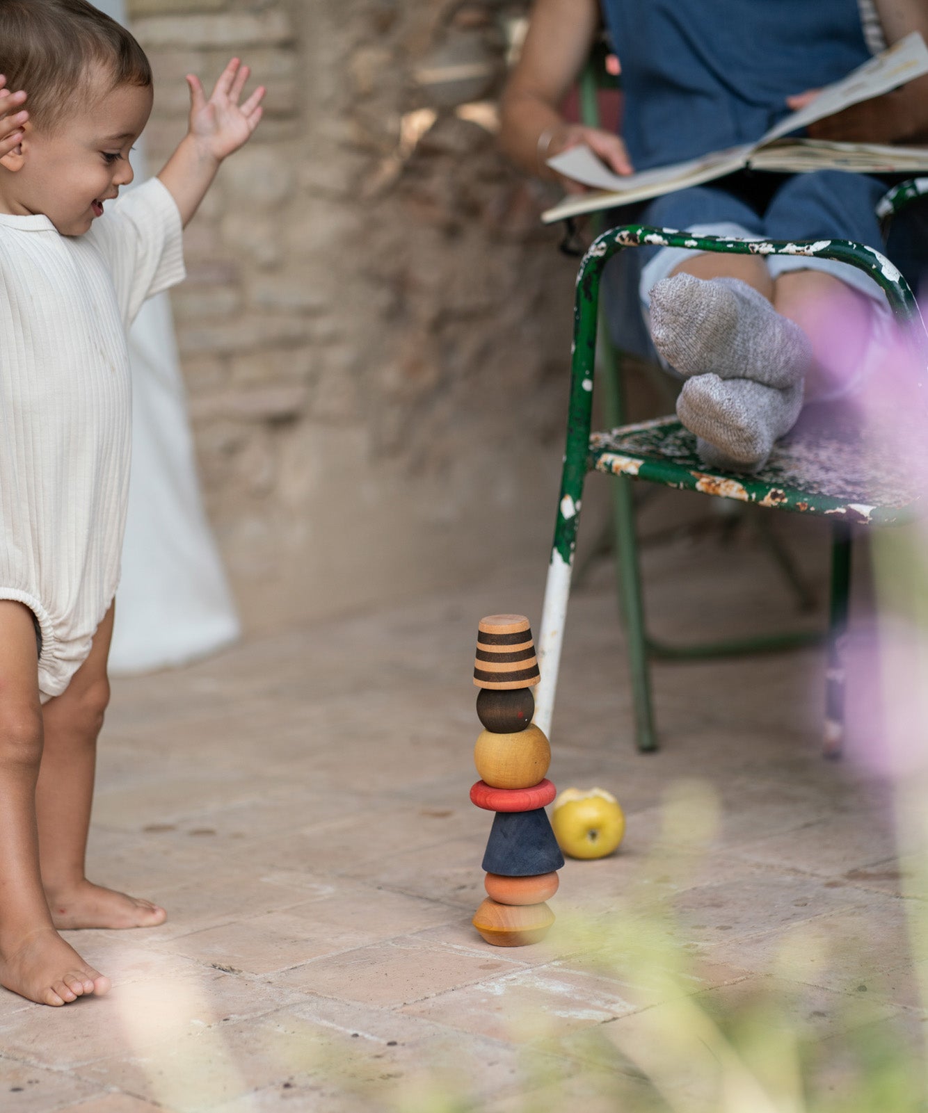 A child playing with the Grapat serendipity wooden stacking set outside on the floor