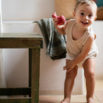 A child playing with the Grapat wooden pink chill bird next to a wooden table