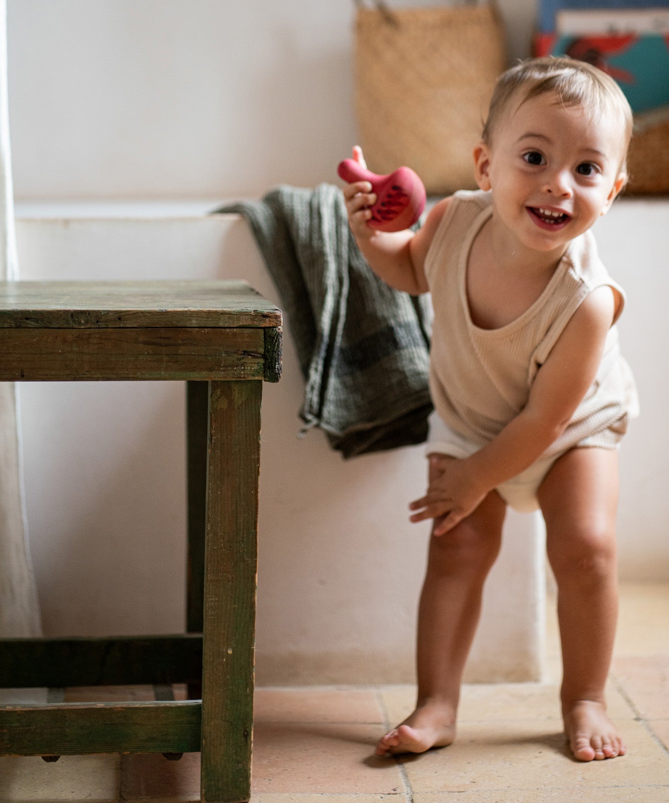 A child playing with the Grapat wooden pink chill bird next to a wooden table