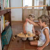 2 children playing with the Grapat wooden pendulum set with wooden blocks on the floor