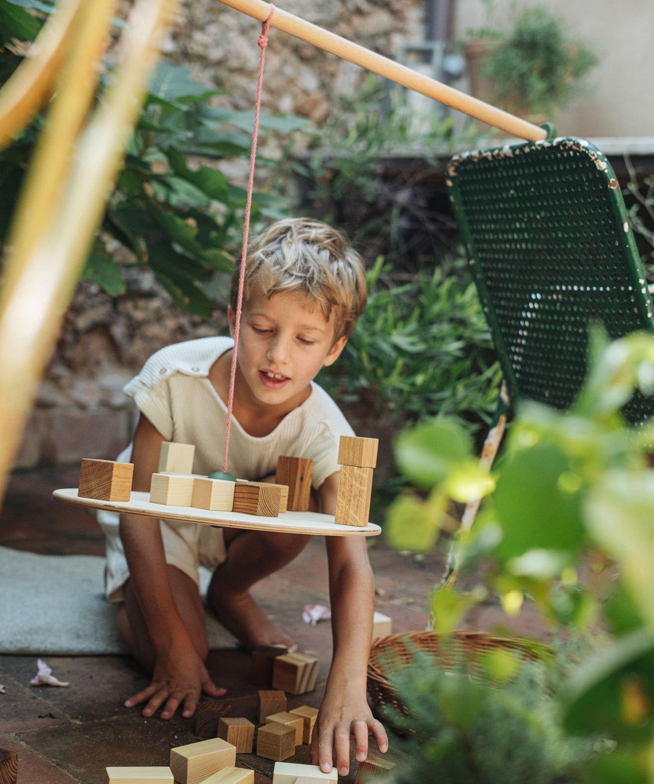 A child playing with the Grapat wooden pendulum set with wooden blocks on the pendulum outside