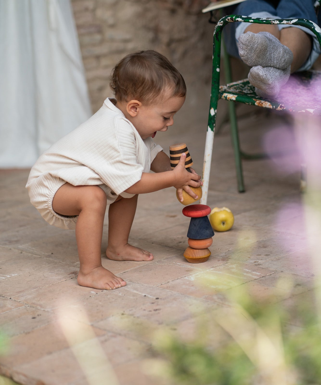 A child playing with the Grapat serendipity stacking set outside on the floor