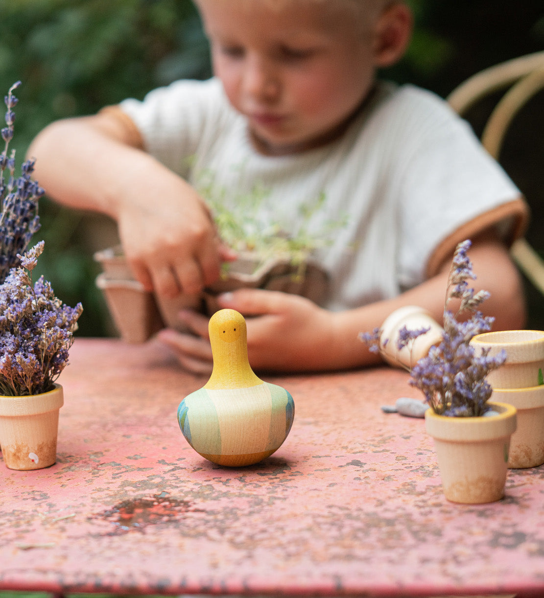 A child playing with the Grapat wooden yellow flowing bird outside on a table