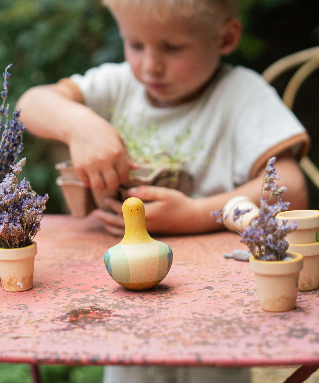 A child playing with the Grapat wooden yellow flowing bird outside on a table