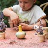 A child playing with the Grapat wooden yellow flowing bird outside on a table