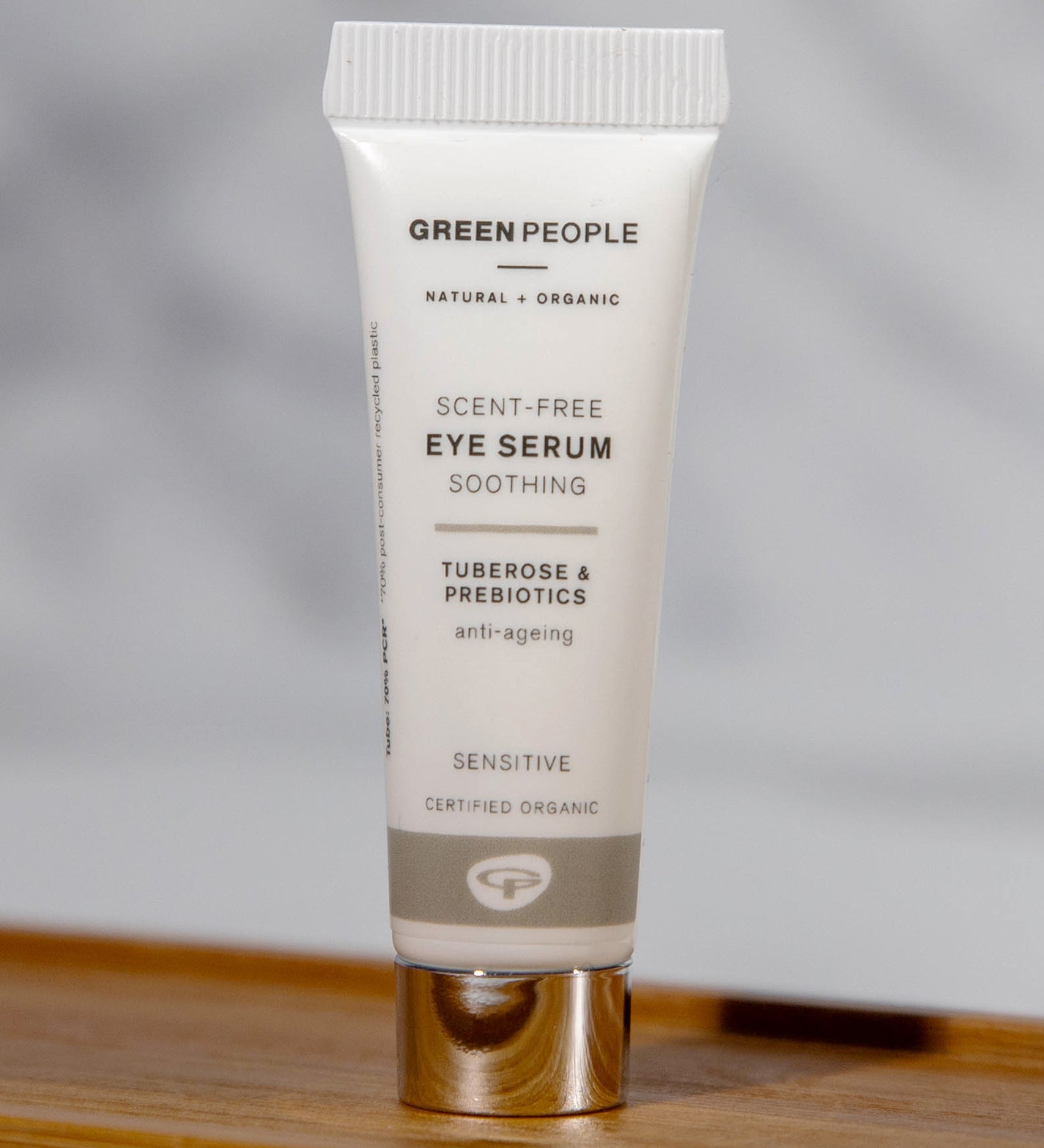 The Green People, natural and organic soothing eye serum is stood on a small wooden table with a grey background