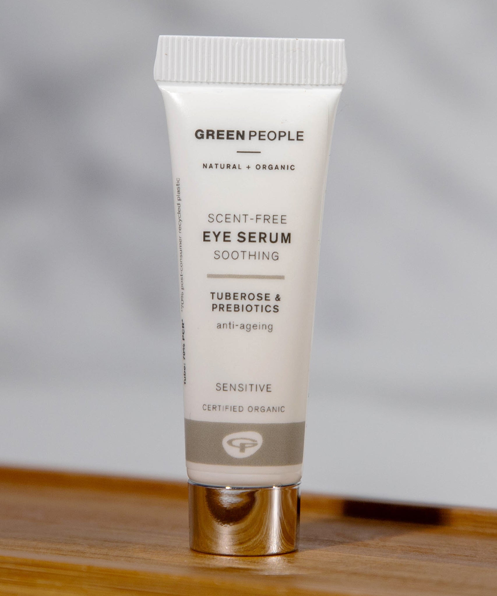 The Green People, natural and organic soothing eye serum is stood on a small wooden table with a grey background