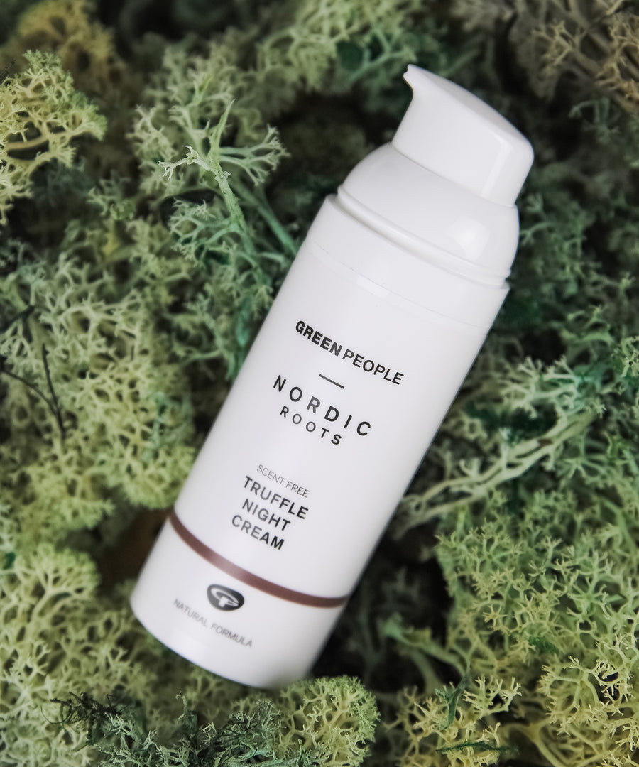 The Green People Nordic Roots Truffle Night Cream - 50ml is laid on a mossy green background 