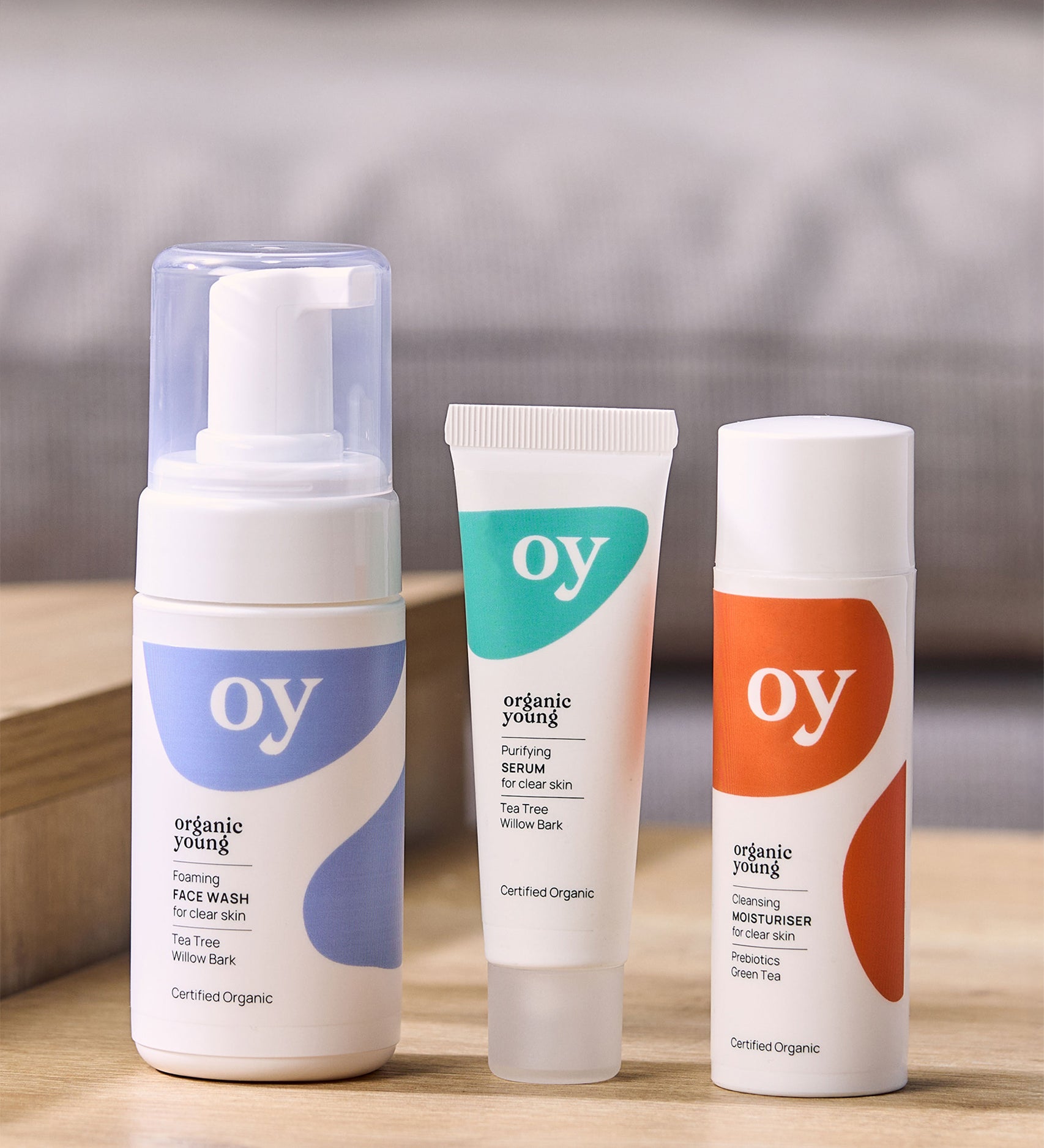 The OY organic, teen and tween skin care gift set with tee tree face wash, purifying serum and cleansing moisturiser which are sat on a wooden table with a grey background