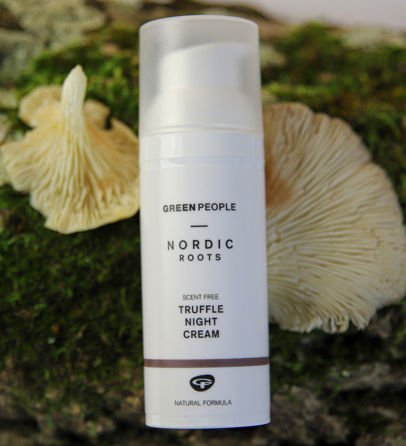 The Green People Nordic Roots Truffle Night Cream is laid on a mossy background with two yellow chanterelle mushrooms