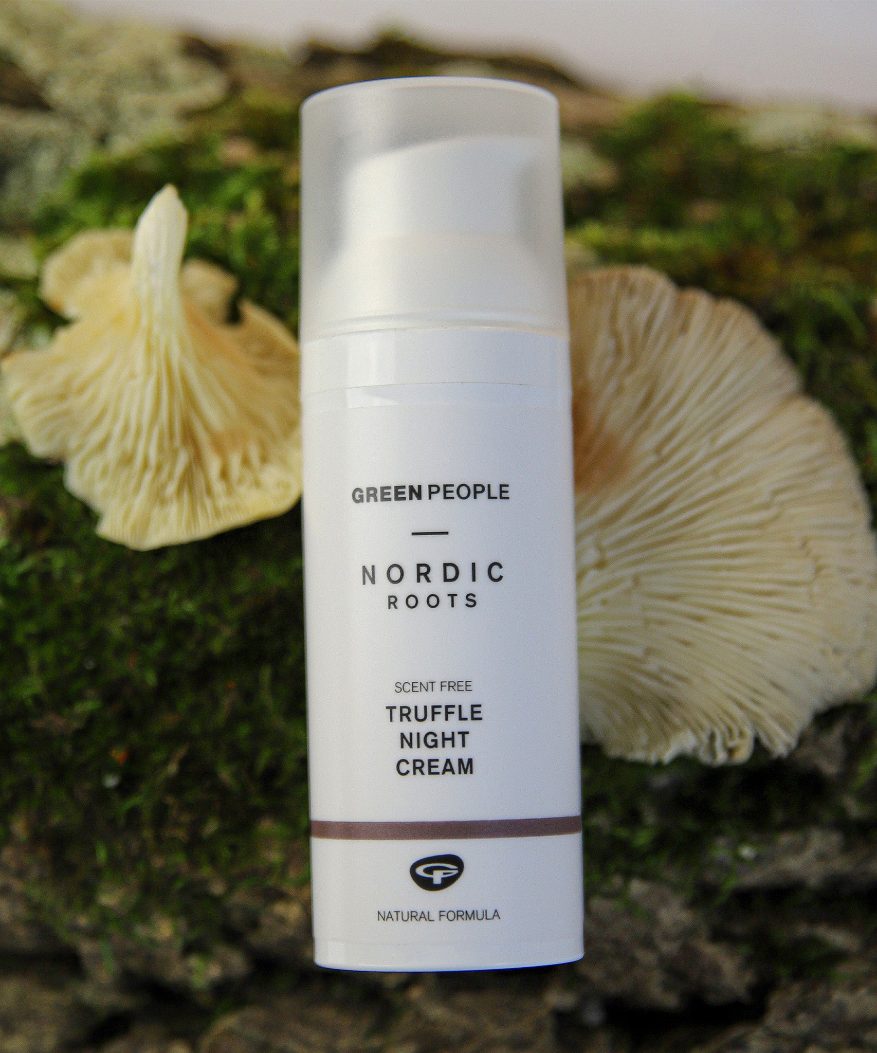 The Green People Nordic Roots Truffle Night Cream is laid on a mossy background with two yellow chanterelle mushrooms