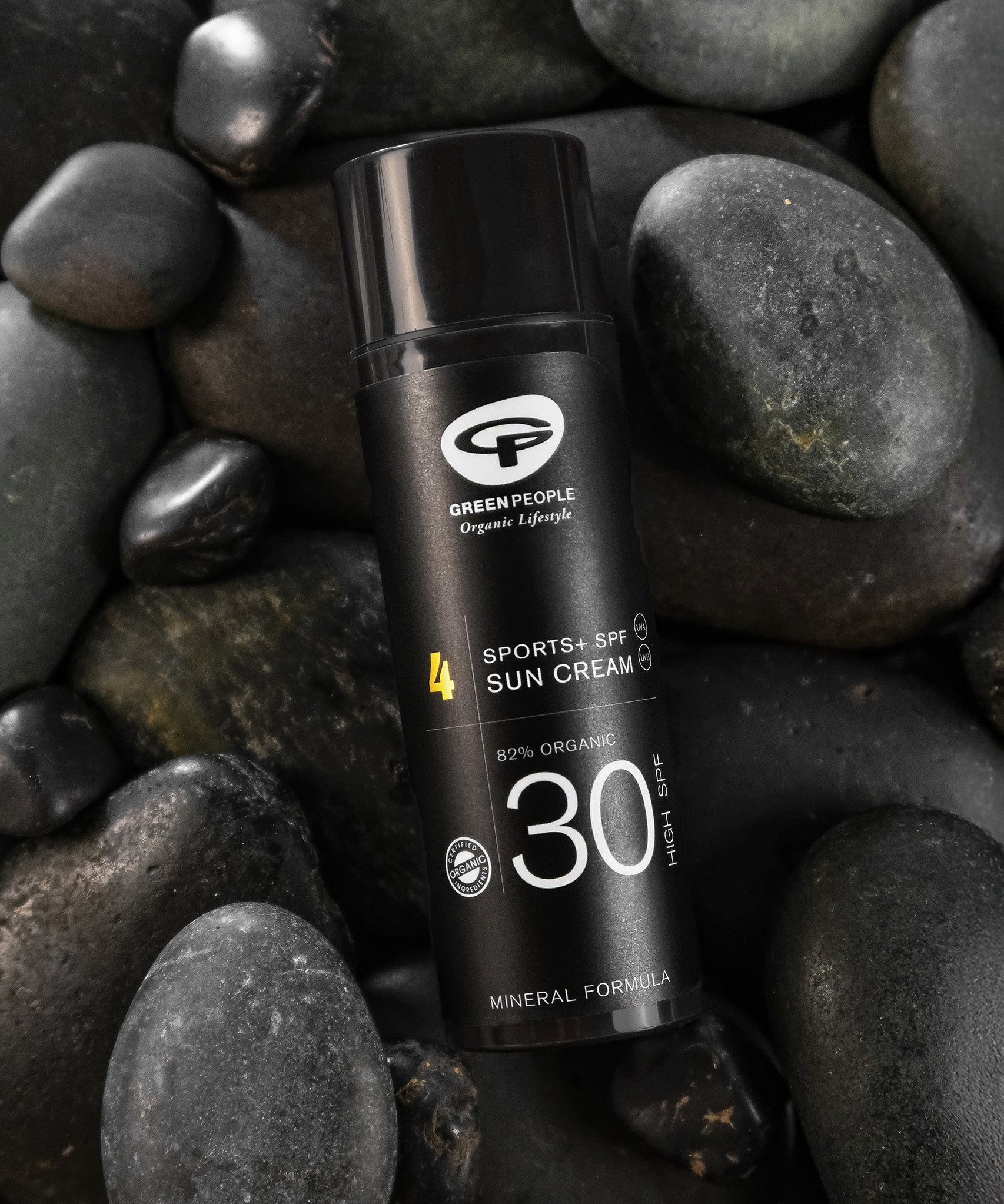 The Green People Sports SPF30 Mineral Facial Sun Cream 50ml laying on grey rocks