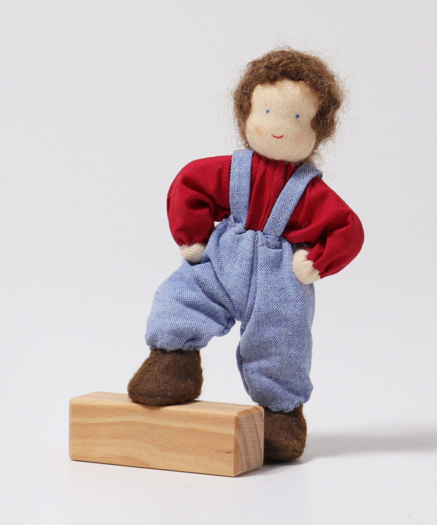 Grimm's Brown Haired Doll - Peter is resting its foot on a block of wood with its arms bent towards its side, to show the flexibility of the dolls limbs